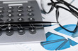 Pen, calculator and glasses on a background of diagrams.
