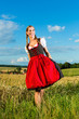 Junge Frau auf der Wiese und trägt Dirndl