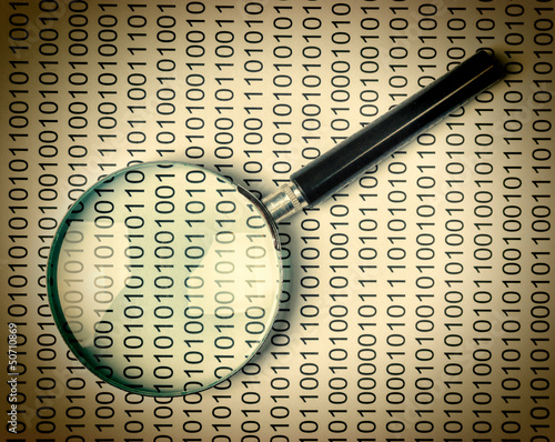Photo: magnifying glass on a binary code magnifying glass on a binary code