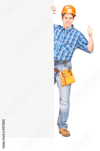 Photo: Full length portrait of a male worker with helmet posing behind Full length portrait of a male worker with helmet posing behind