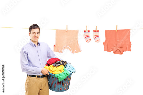 Photo: Smiling guy holding a laundry bin and a laundry line with clothe Smiling guy holding a laundry bin and a laundry line with clothe