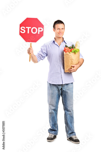 Photo: Stop and shop here Full length portrait of a male holding a pape Stop and shop here Full length portrait of a male holding a pape