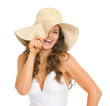 Smiling young woman in swimsuit playing with hat