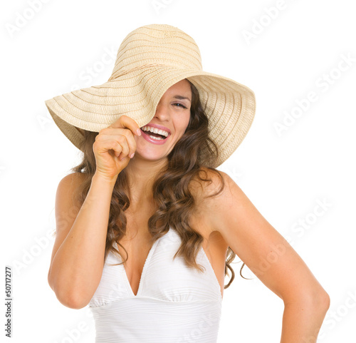 Photo: Smiling young woman in swimsuit playing with hat Smiling young woman in swimsuit playing with hat