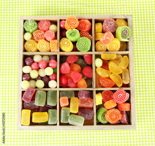 Photo: Multicolor candies in wooden box, on color background Multicolor candies in wooden box, on color background