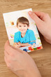 Photos in hands on wooden table