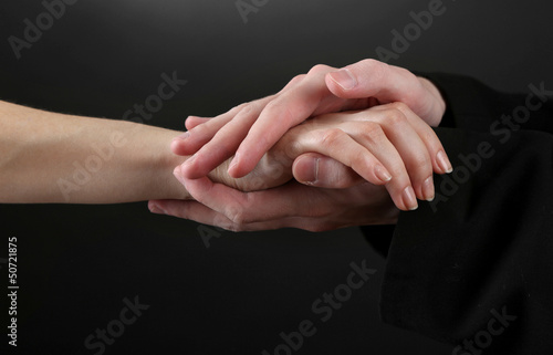 Photo: Priest holding woman hand, on black background Priest holding woman hand, on black background