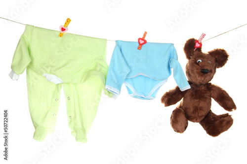 Photo: Baby clothes hanging on clothesline, isolated on white Baby clothes hanging on clothesline, isolated on white