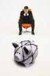Photo: Worried businessman on chair and piggybank tied with rope representing financial difficulties Worried businessman on chair and piggybank tied with rope representing financial difficulties