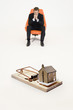 Photo: Model home on mouse trap with worried businessman sitting on chair representing increasing real estate rates Model home on mouse trap with worried businessman sitting on chair representing increasing real estate rates