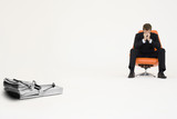 Foto: Wad of cash on mouse trap with worried businessman sitting on chair representing financial difficulties Wad of cash on mouse trap with worried businessman sitting on chair representing financial difficulties