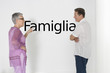 Photo: Couple discussing family issues against white wall with Italian text "Famiglia" Couple discussing family issues against white wall with Italian text "Famiglia"