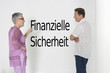 Photo: Couple discussing financial security against white wall with German text "Finanzielle Sicherheit" Couple discussing financial security against white wall with German text "Finanzielle Sicherheit"