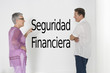Photo: Couple discussing financial security against white wall with Spanish text "Seguridad Financiera" Couple discussing financial security against white wall with Spanish text "Seguridad Financiera"
