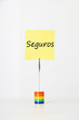 Photo: Sticky notepaper with Spanish text "seguros" (Insurance) clipped to a multicolored card holder Sticky notepaper with Spanish text "seguros" (Insurance) clipped to a multicolored card holder