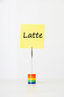 Photo: Sticky notepaper with Italian text "latte" (milk) clipped to a multicolored card holder Sticky notepaper with Italian text "latte" (milk) clipped to a multicolored card holder
