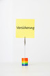 Photo: Sticky notepaper with German text "Versicherung" (Insurance) clipped to a multicolored card holder Sticky notepaper with German text "Versicherung" (Insurance) clipped to a multicolored card holder