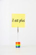 Photo: Sticky notepaper with French text "il est plus" (It's over) clipped to a multicolored card holder Sticky notepaper with French text "il est plus" (It's over) clipped to a multicolored card holder