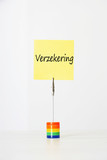 Photo: Sticky notepaper with Dutch text "Verzekering" (Insurance) clipped to a multicolored card holder Sticky notepaper with Dutch text "Verzekering" (Insurance) clipped to a multicolored card holder