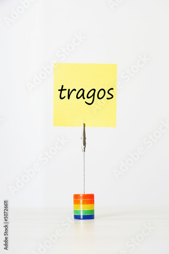 Photo: Sticky notepaper with Spanish text "Tragos" (Drinks) clipped to a multicolored card holder Sticky notepaper with Spanish text "Tragos" (Drinks) clipped to a multicolored card holder