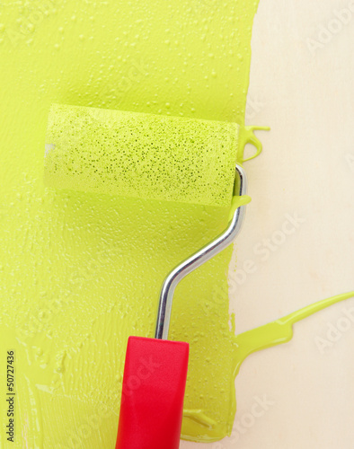 Photo: Paint roller brush with green paint, on wooden background Paint roller brush with green paint, on wooden background