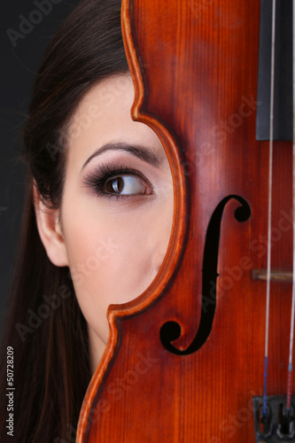 Photo: Beautiful young girl with violin on grey background Beautiful young girl with violin on grey background