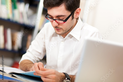 Photo: Student reading a book in a library Student reading a book in a library
