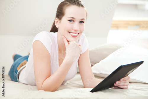 Photo: Attraktive junge Frau liegt auf dem Bett mit tablet-pc Attraktive junge Frau liegt auf dem Bett mit tablet-pc