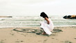 Woman showing love sign to partner on a beach