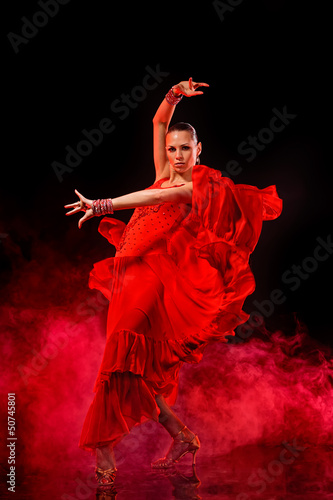 Photo: Young woman dancing Latino on dark smoky background Young woman dancing Latino on dark smoky background