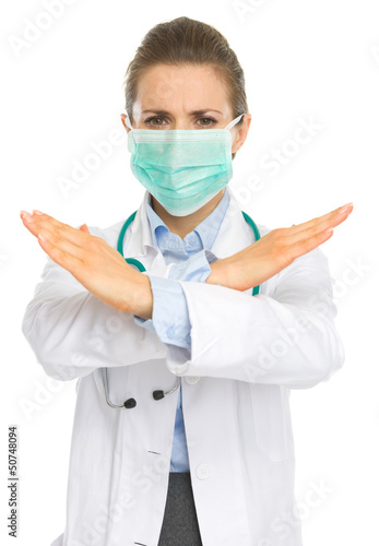 Photo: Concerned medical doctor woman in mask showing stop gesture Concerned medical doctor woman in mask showing stop gesture