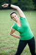 Overweight woman stretching in the park