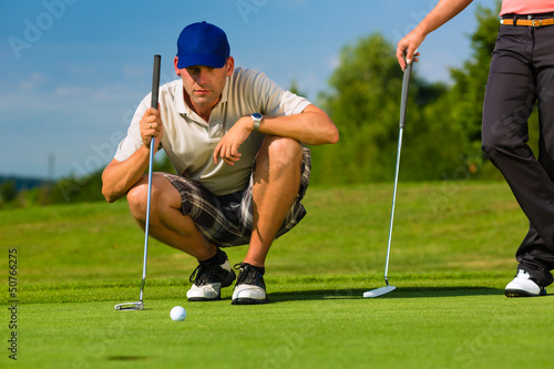 Photo: Young sportive couple playing golf on a course Young sportive couple playing golf on a course