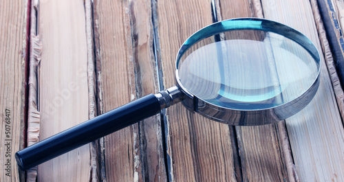 Photo: Magnifying glass over the stack of books Magnifying glass over the stack of books