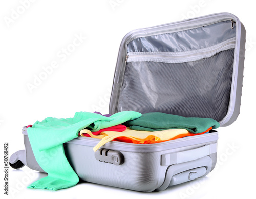 Photo: Open silver suitcase with clothing isolated on white Open silver suitcase with clothing isolated on white