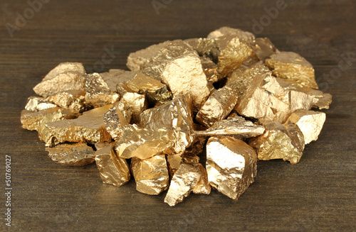 Photo: Golden nuggets on wooden background Golden nuggets on wooden background