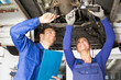 Mechanics repairing a car on hydraulic ramp