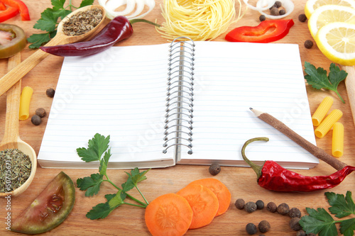 Photo: Notebook for recipes, vegetables and spices on wooden table. Notebook for recipes, vegetables and spices on wooden table.