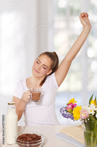 Photo: Beautiful young woman streching herself while holding a glass of Beautiful young woman streching herself while holding a glass of