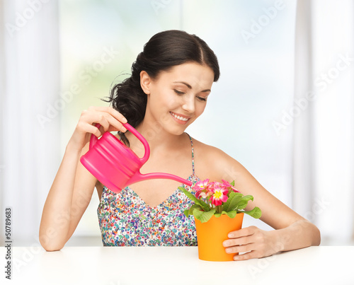 Photo: housewife with flower in pot and watering can housewife with flower in pot and watering can