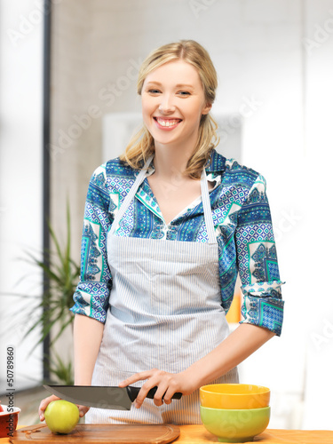Photo: beautiful woman in the kitchen cutting an apple beautiful woman in the kitchen cutting an apple