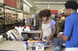 Foto: Portrait of an African American female store clerk standing at checkout counter scanning item serving male customer Portrait of an African American female store clerk standing at checkout counter scanning item serving male customer