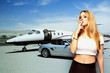 Foto: Portrait of young woman smoking cigarette with car and airplane in the background Portrait of young woman smoking cigarette with car and airplane in the background