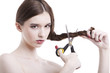 Photo: Portrait of beautiful young woman with scissors cutting her hair over white background Portrait of beautiful young woman with scissors cutting her hair over white background