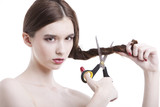 Photo: Portrait of beautiful young woman with scissors cutting her hair over white background Portrait of beautiful young woman with scissors cutting her hair over white background