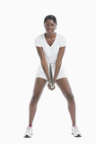Foto: Portrait of young woman holding tennis racket standing over white background Portrait of young woman holding tennis racket standing over white background
