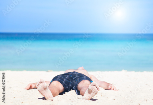 Photo: man lies on a peschchany beach on an ocean coast man lies on a peschchany beach on an ocean coast