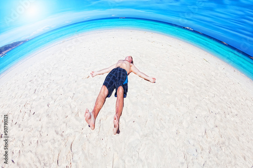 Photo: man lies on a peschchany beach on an ocean coast man lies on a peschchany beach on an ocean coast