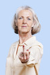 Foto: Senior woman in casuals making rebellious hand gesture against blue background Senior woman in casuals making rebellious hand gesture against blue background