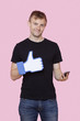 Foto: Portrait of a happy young man with cell phone holding fake like button over pink background Portrait of a happy young man with cell phone holding fake like button over pink background